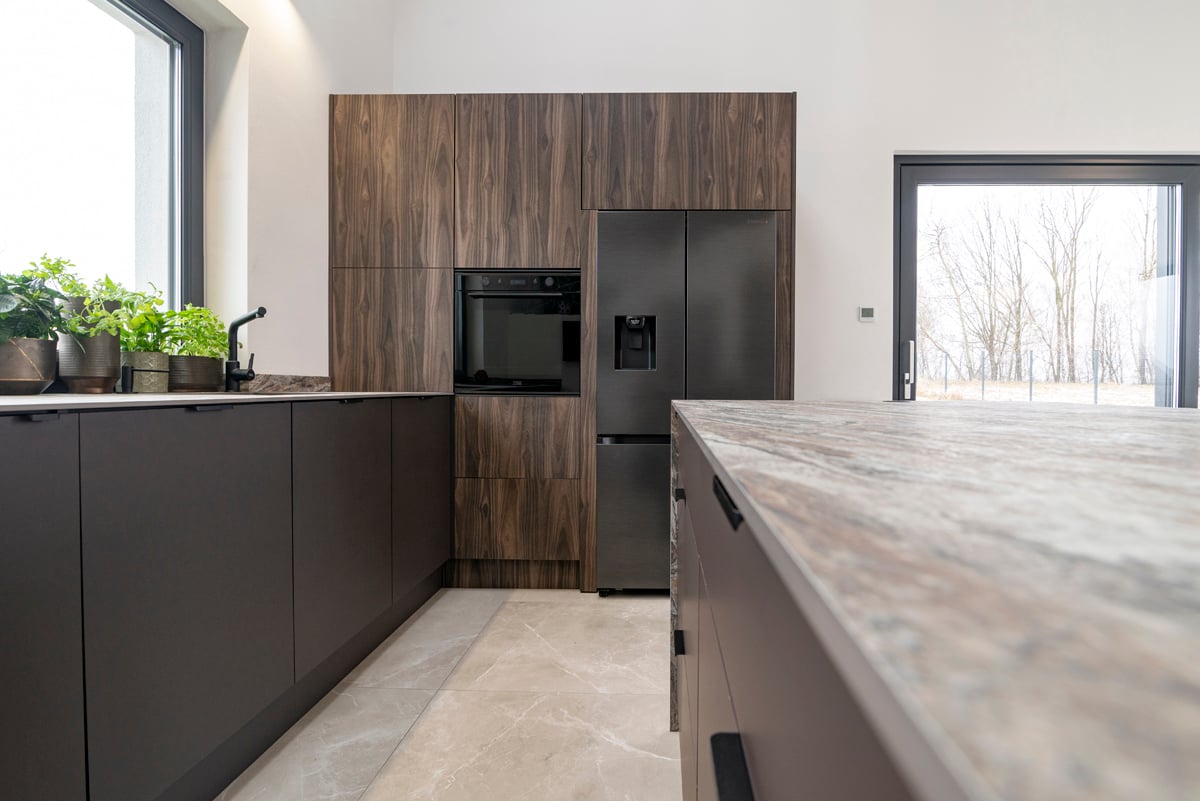 Floor-to-ceiling walnut cabinet run with marble worktops