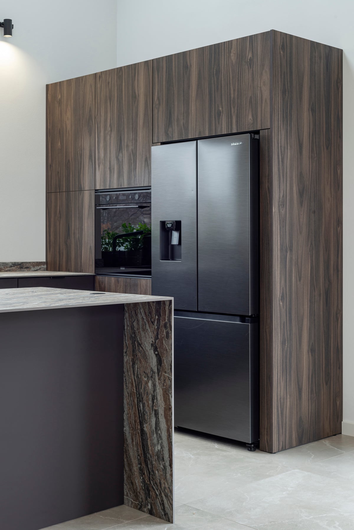Black fridge integrated in walnut cabinet tower