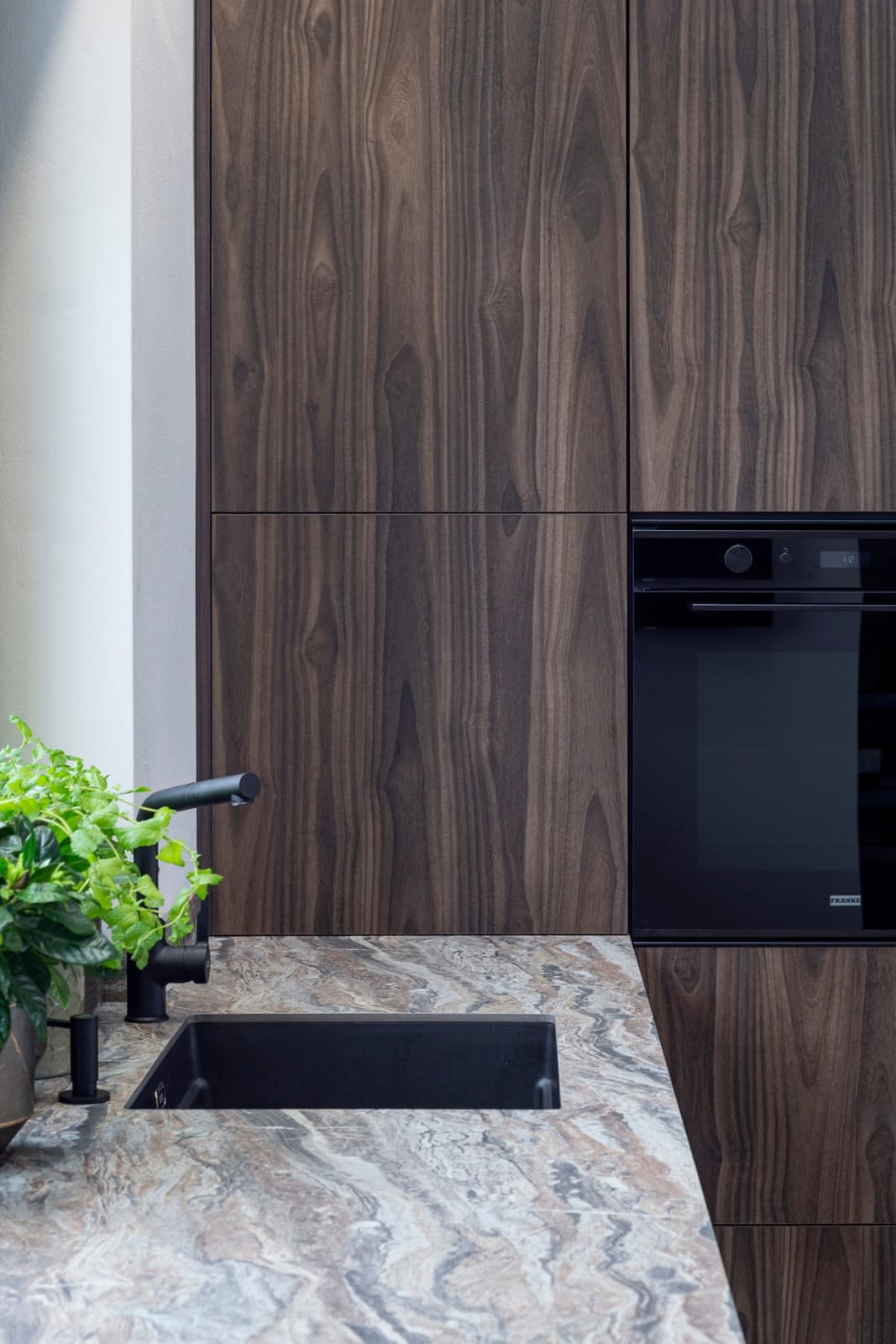 Keuken spoelzone met walnoten kasten en ingebouwde oven