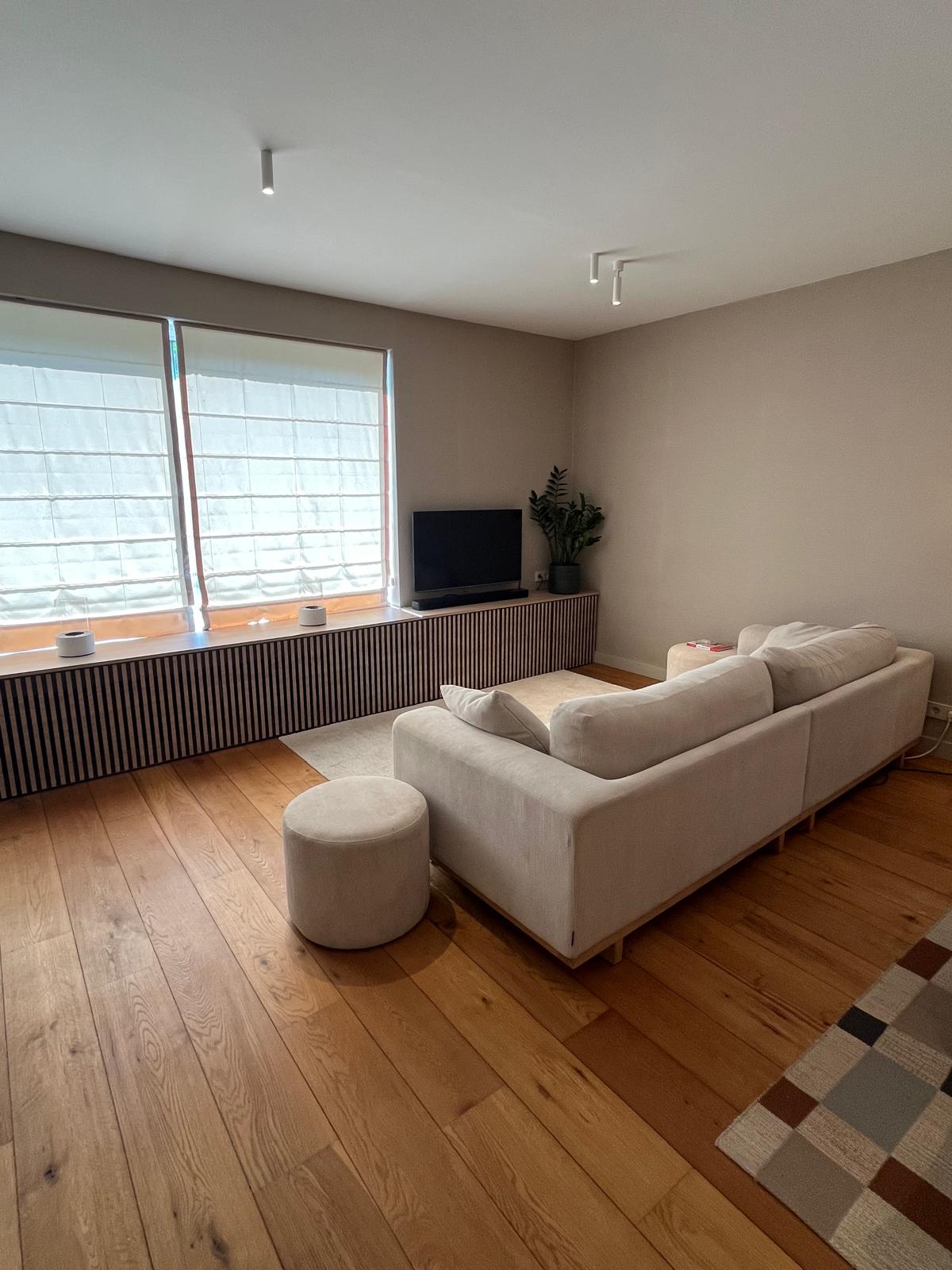 Woonkamer met latten eiken media-meubel onder de ramen