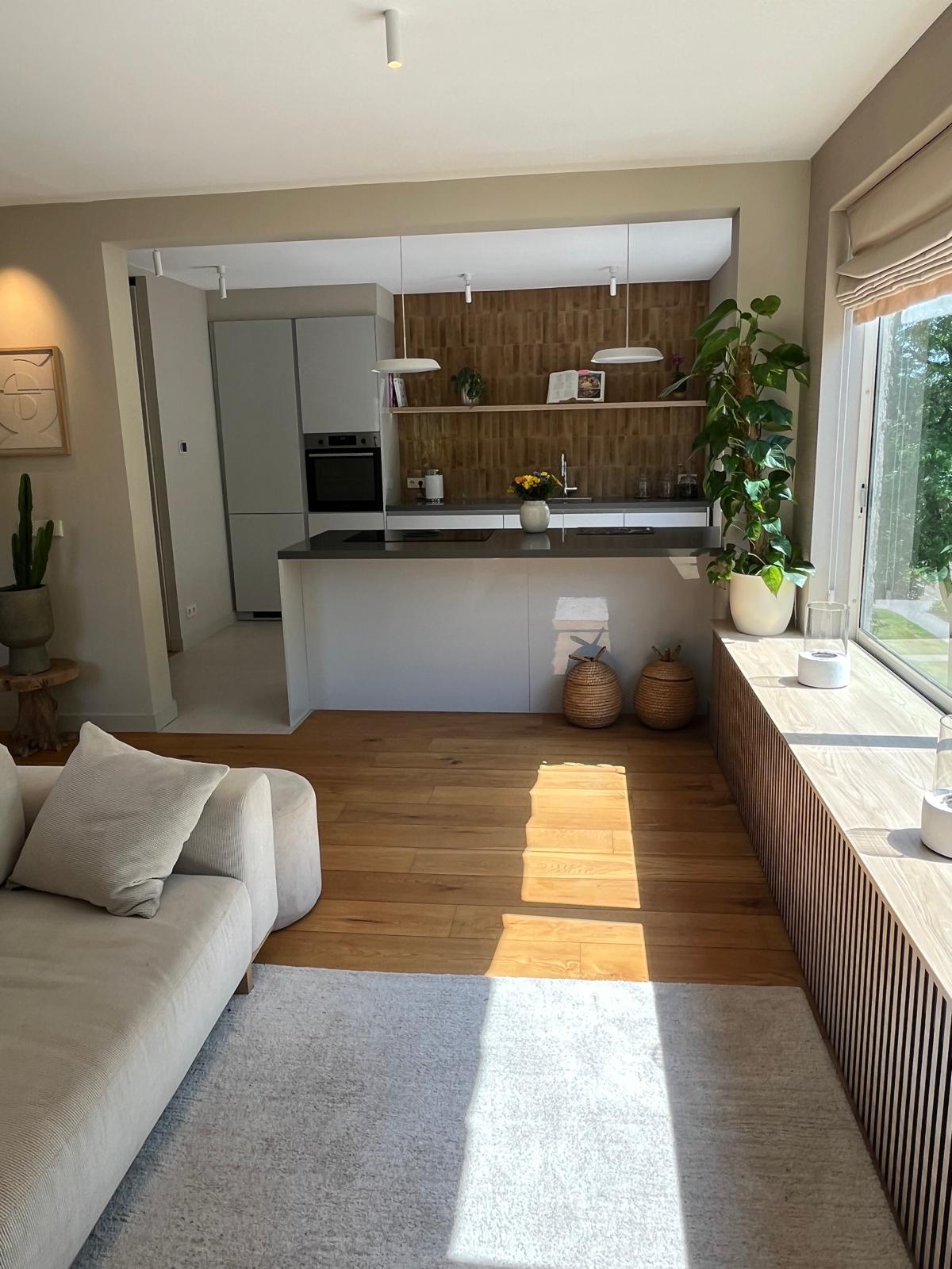 Overzicht keuken en woonkamer met kookeiland en tuinzicht