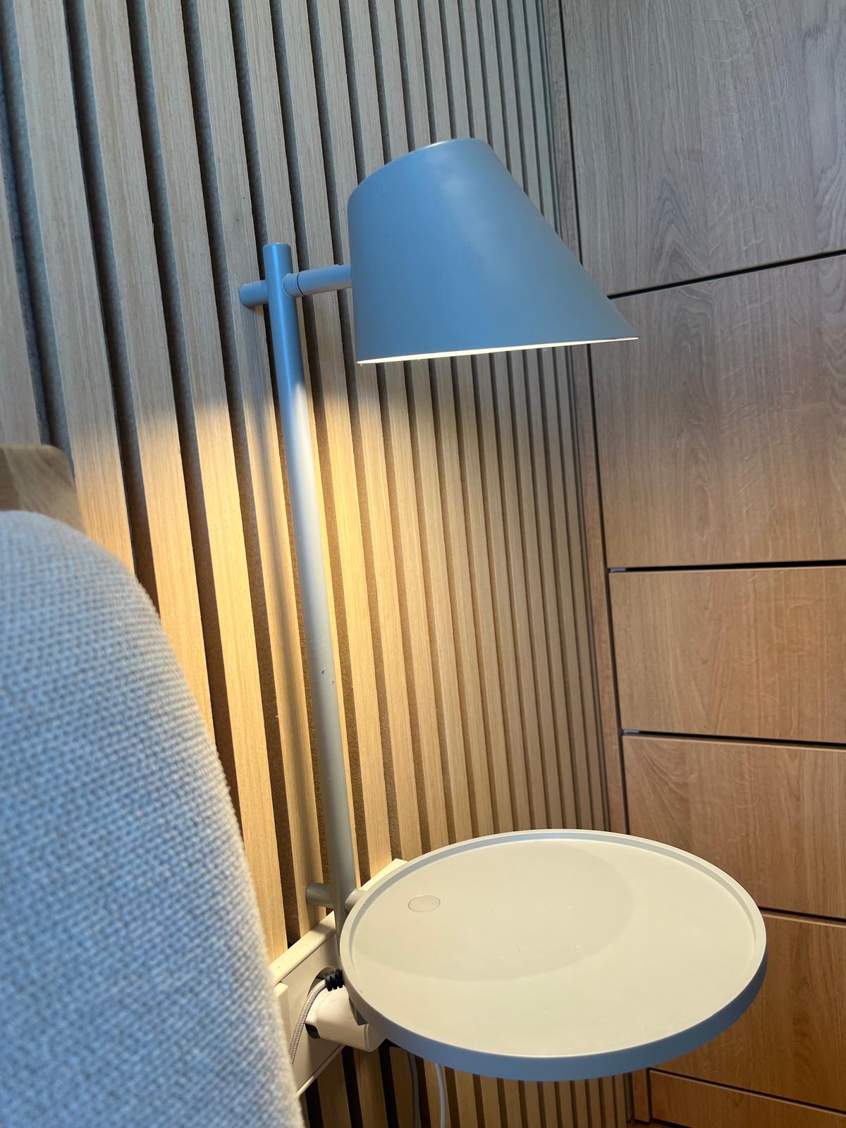 Wandlamp en nachtkastje tegen latten eiken hoofdbordwand