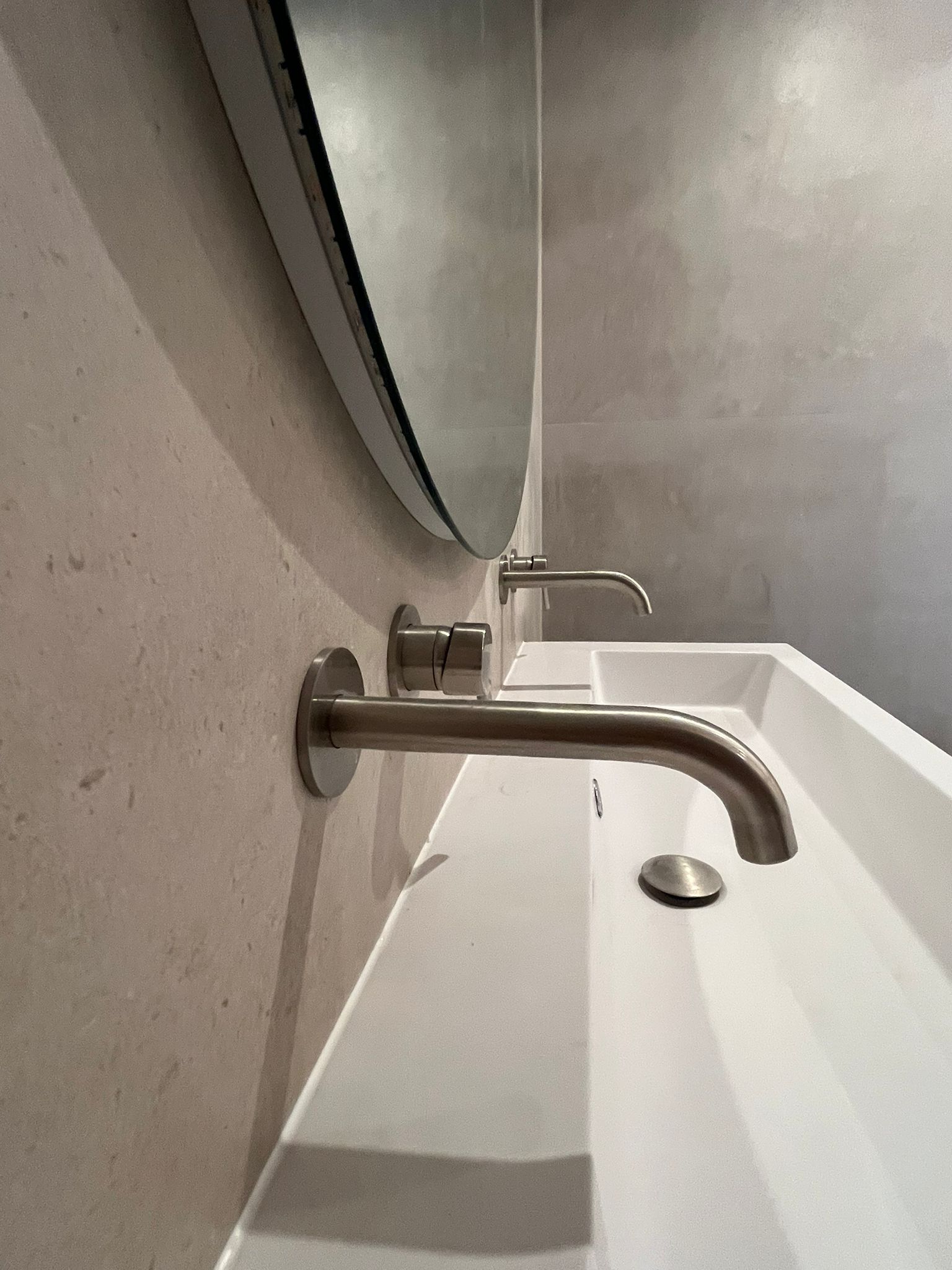 Wastafeldetail met wandkranen en ronde spiegel